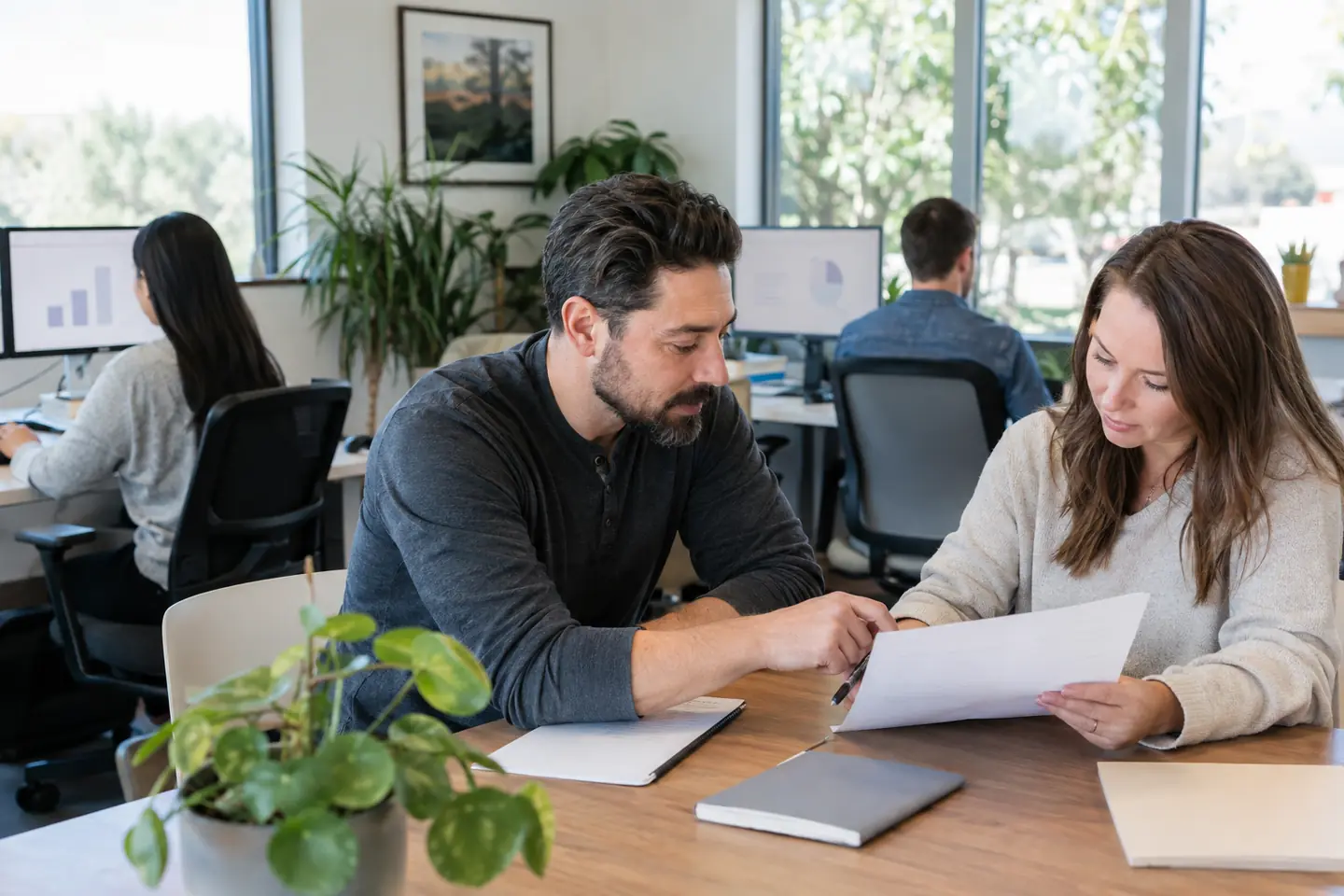 Four colleagues work together at desks and a table in a bright company office