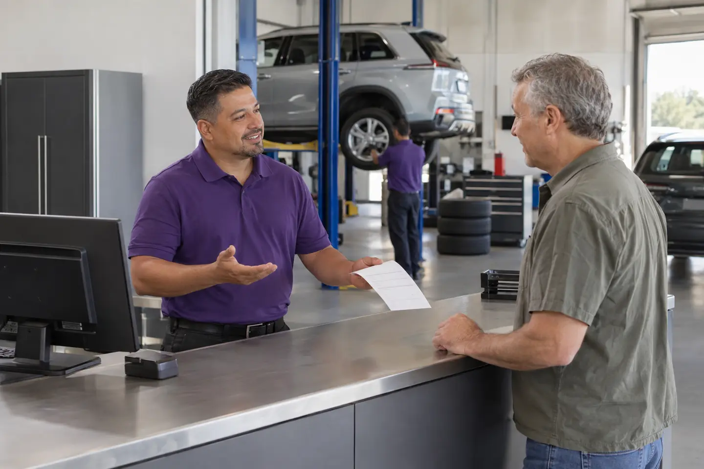 An associate hands a customer his receipt at the service counter and answers a question
