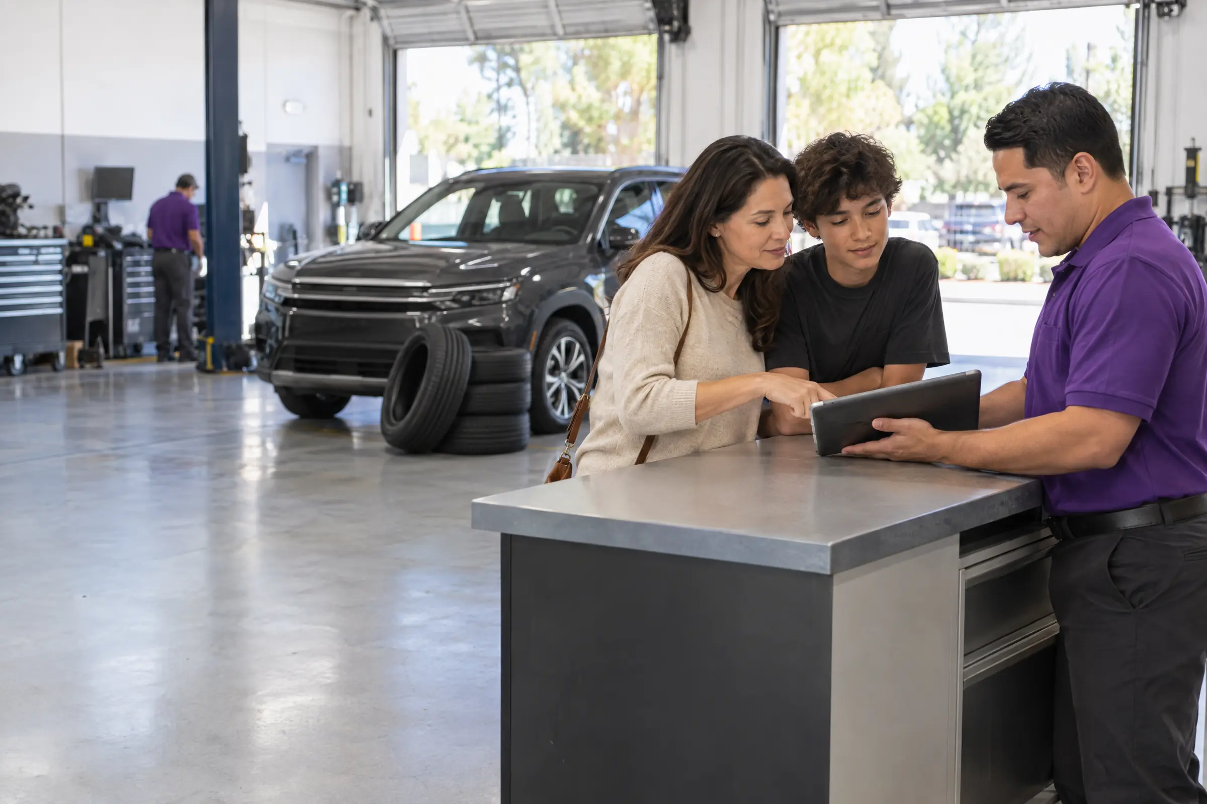 A mother and her son review an estimate on a tablet with an associate at the service counter