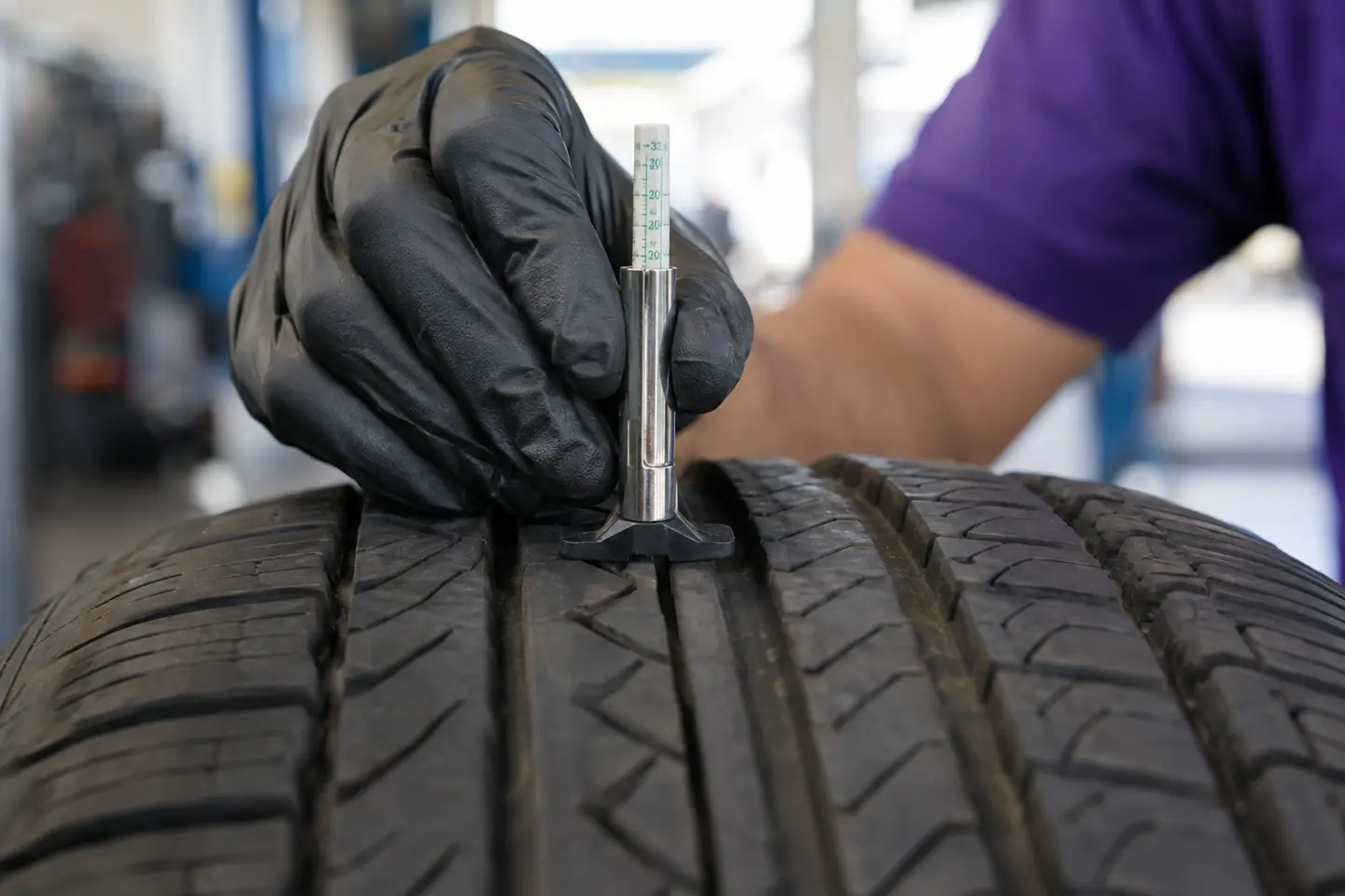 A tread depth gauge pressed into a tire’s main groove