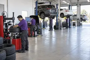 A spotless service floor with technicians at a tire changer, balancer and lift
