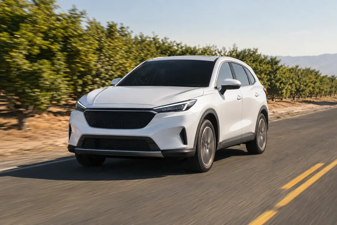 A crossover on a straight country road between orchards