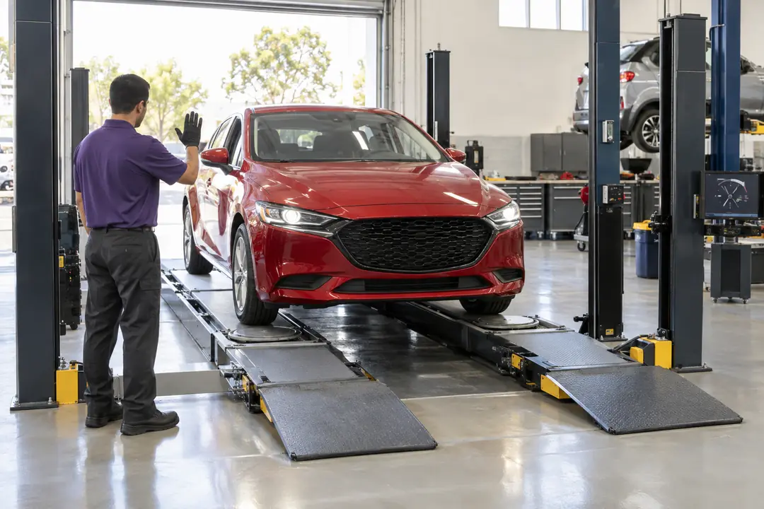 A hatchback rolling onto an alignment rack, guided by a technician
