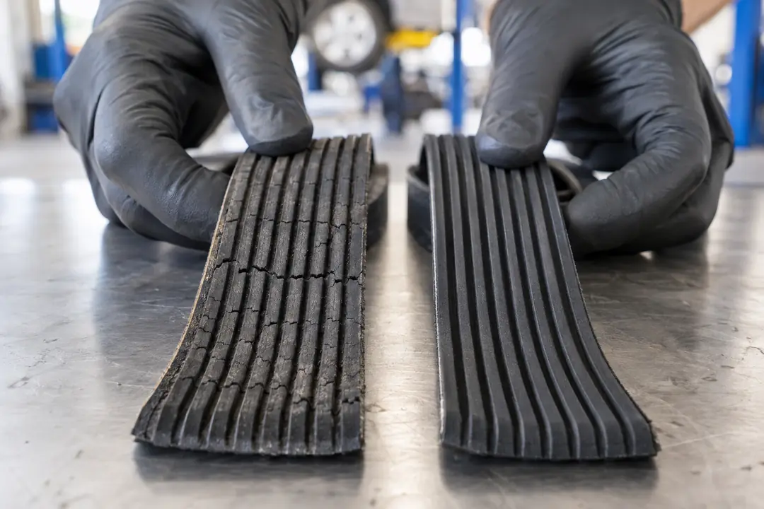 An old serpentine belt with cracked ribs beside a new belt