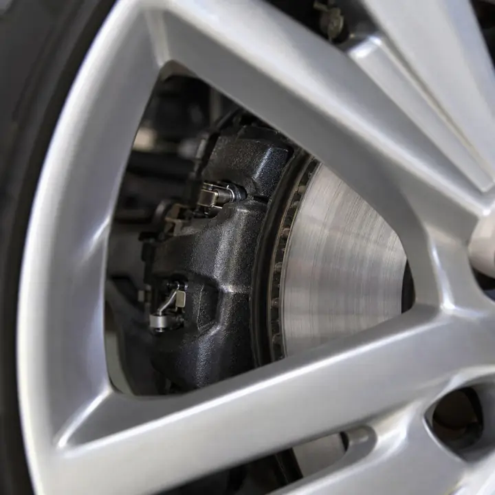 A brake caliper and rotor seen through the spokes of a wheel
