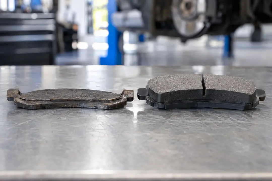 A worn brake pad with little friction material beside a new pad