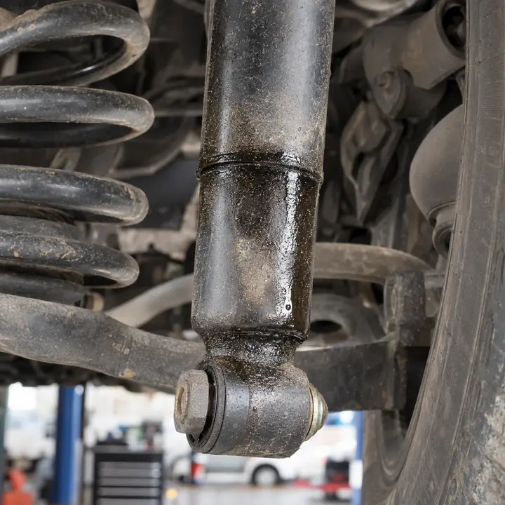 Oil running down the body of a worn shock absorber