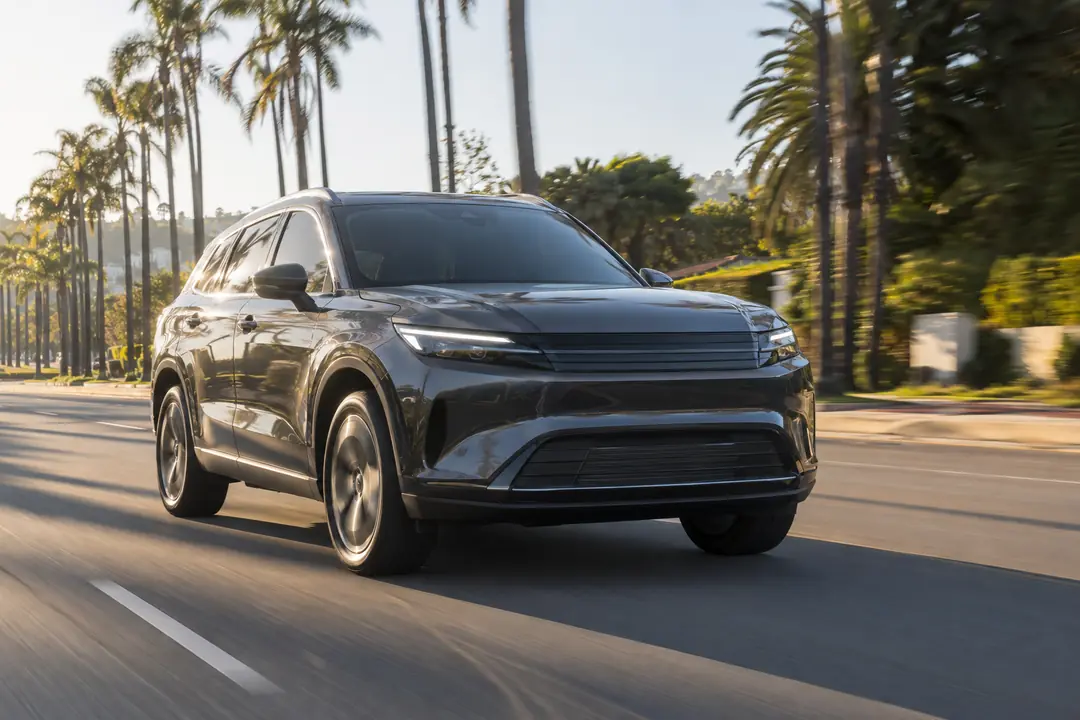 An SUV driving straight down a palm-lined street